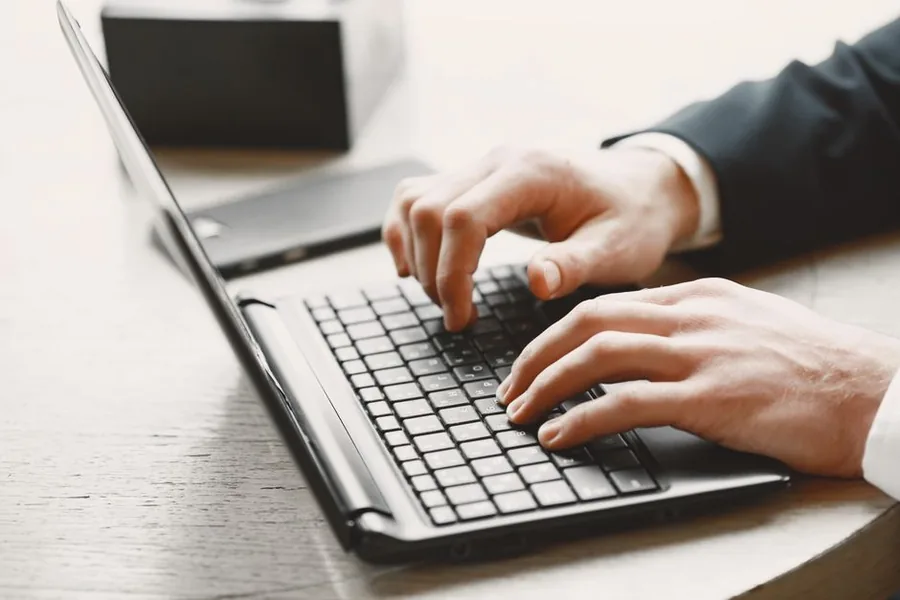A suited professional at a laptop reviewing employee and payroll records A suited professional at a laptop reviewing employee and payroll records