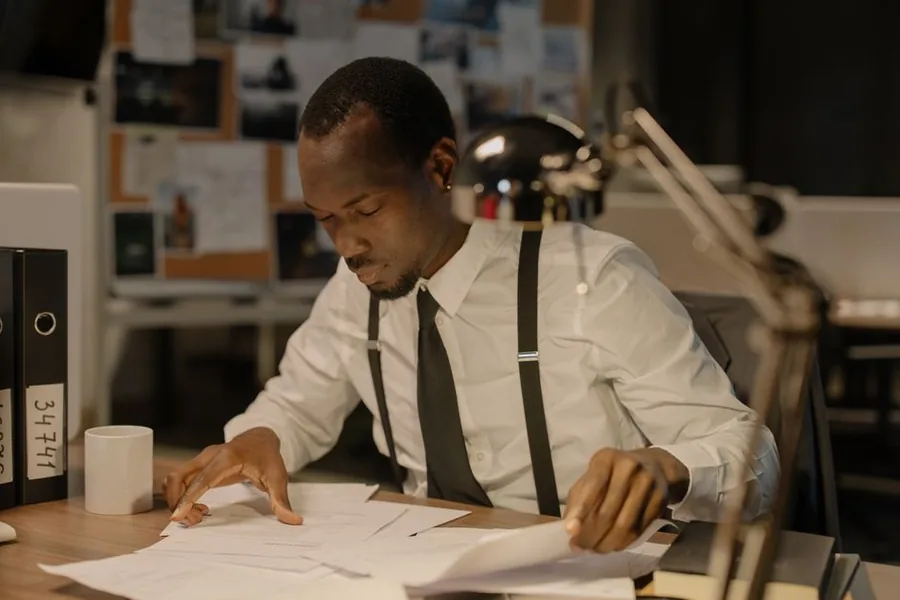 A business owner reviewing import paperwork and VAT records at a desk, checking figures for a postponed VAT accounting return A business owner reviewing import paperwork and VAT records at a desk, checking figures for a postponed VAT accounting return
