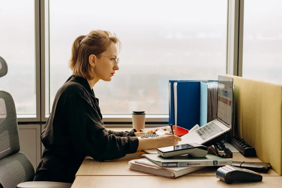 A finance professional reviewing company accounts and tax figures in a UK corporate office A finance professional reviewing company accounts and tax figures in a UK corporate office