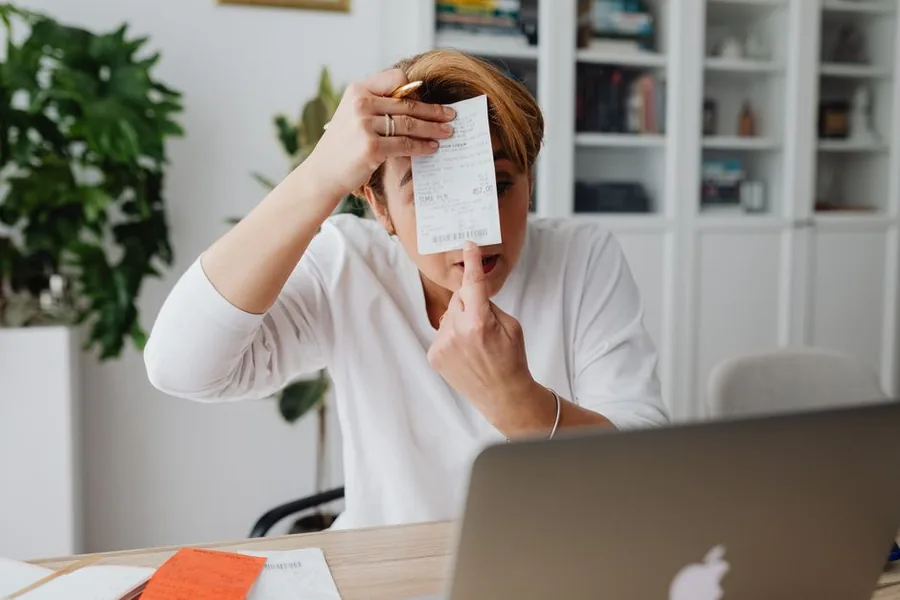 A self-assessment taxpayer looking stunned at a bill while checking the figures on her laptop A self-assessment taxpayer looking stunned at a bill while checking the figures on her laptop