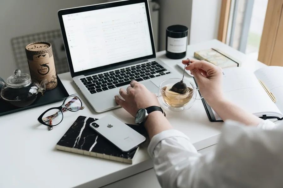 A remote employee working at a tidy home desk with a laptop, notebook and cup of tea A remote employee working at a tidy home desk with a laptop, notebook and cup of tea