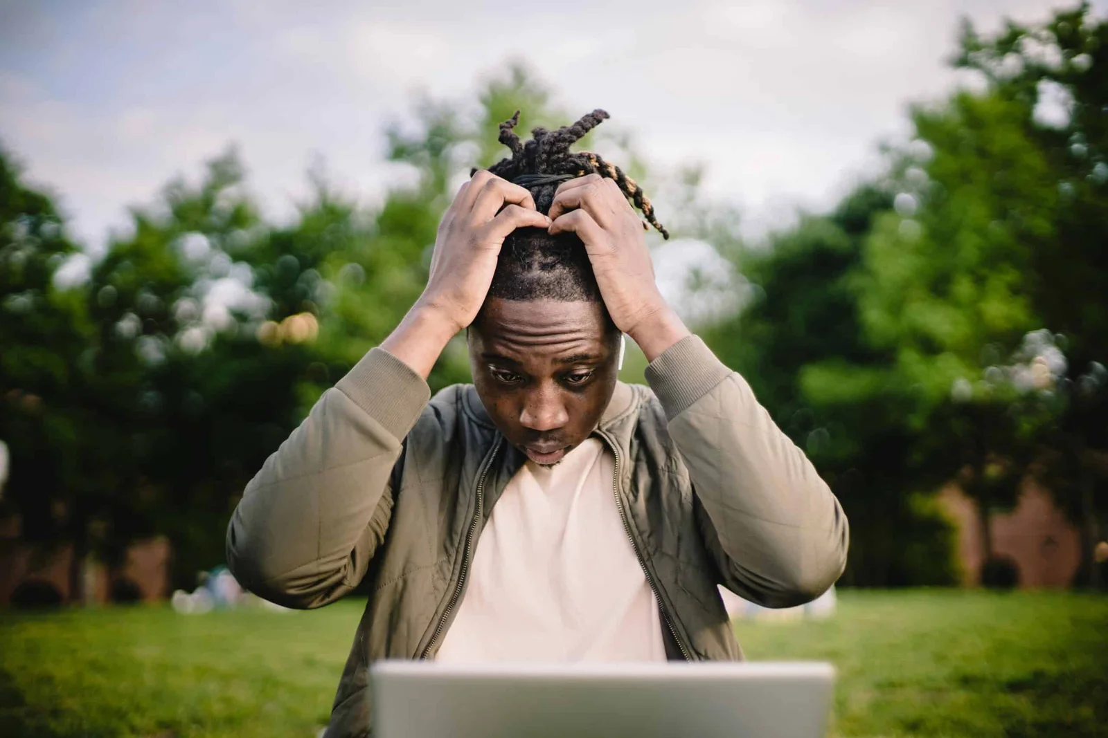 A person feeling stressed and holding their head in frustration while using a laptop.