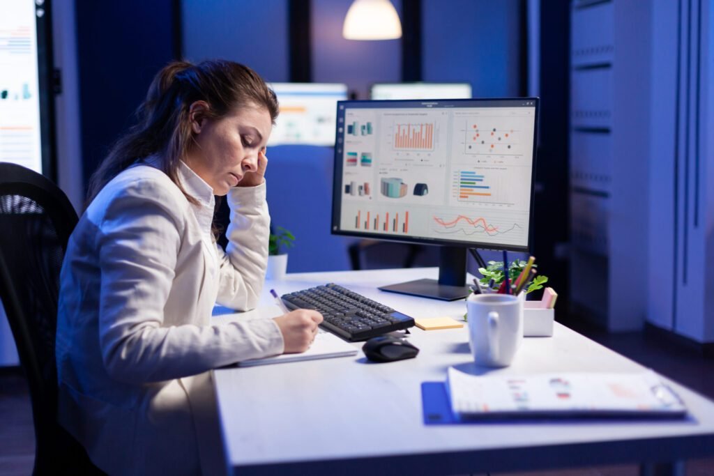 An accountant working at a desk with multiple monitors and documents.