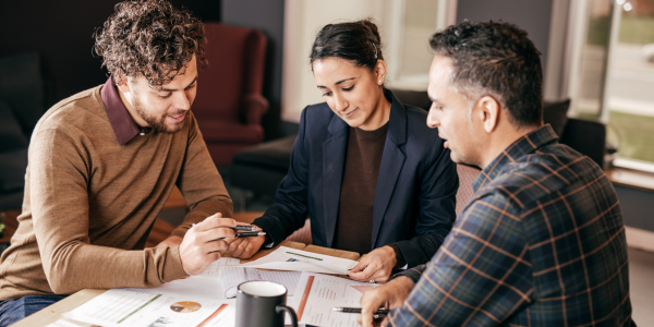 Two accountants discussing financial reports at a table with documents and a coffee mug, focusing on tax planning.