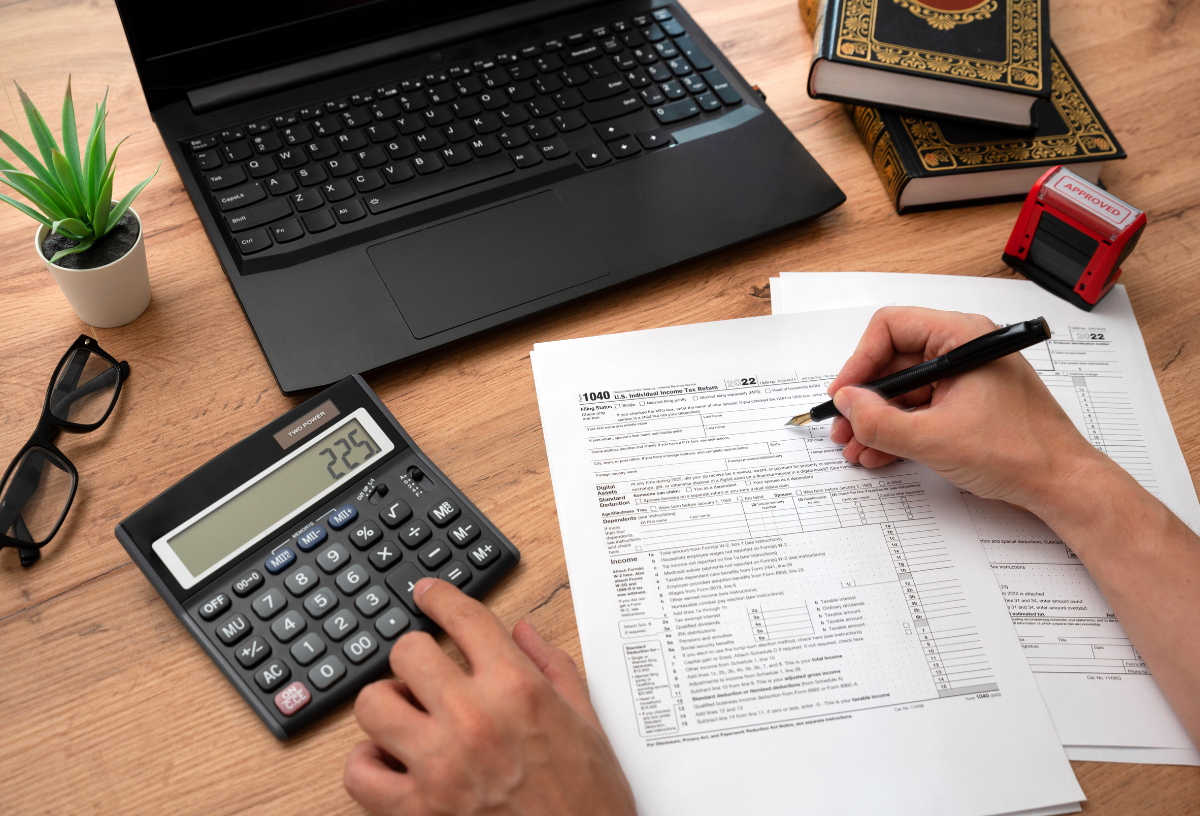 Person filing taxes using laptop, documents, and calculator