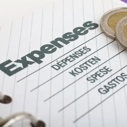 A notebook with the word "Expenses" written on it next to coins.
