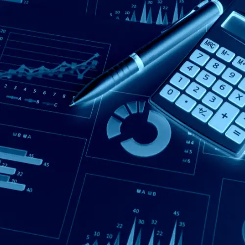 A close-up of a calculator, pen, and financial charts on a desk.