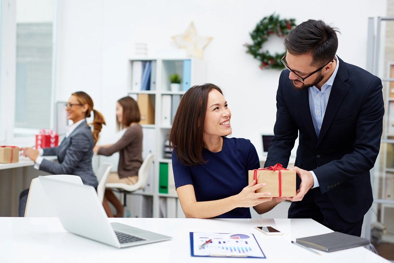 Company director giving employees small appreciation gifts.